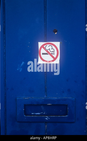 Detail des maroden blau Holz Brett Tür mit Briefkasten und rostigen Reißnadel mit achtlos geschnitten und platziert Aufkleber Rauchen verboten Stockfoto