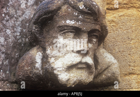 Nahaufnahme von verwitterter Sandstein geschnitzten Kopf und Schultern des bärtigen Mann mit Flechten als Corbel, steinernen Bogen Stockfoto