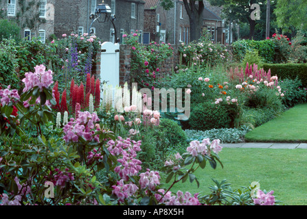 Rosa Rhododendron und rote Lupinen mit rosa Orientalischer Mohn im Sommer Grenze in ummauerten Stadtgarten mit weißes Tor Stockfoto