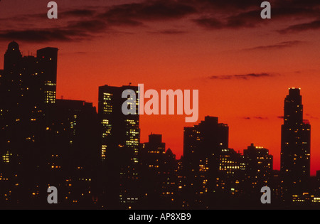 USA, Skyline von New York City, Midtown Manhattan. Die silhouettengetupften Wolkenkratzer stehen bei Sonnenuntergang vor einem roten Himmel. Central Park South Stockfoto