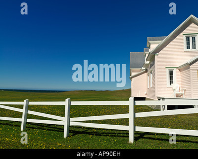 Kanada Quebec Gaspesie Rivière la Madeleine Rosa Haus und mit weißen Zaun Greenfield vor blauem Himmel Stockfoto