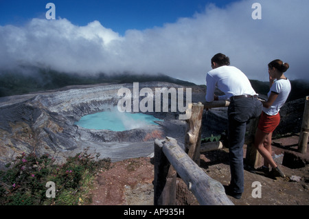 Junges Paar auf der Suche in den dampfenden Krater des aktiven Vulkan Poas, Parque Nacional Volcan Poas, Costa Rica Stockfoto