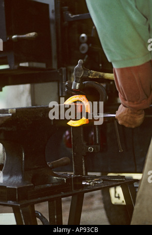 Hufschmied bilden rote heiße Hufeisen mit Hammer am Amboss Stockfoto