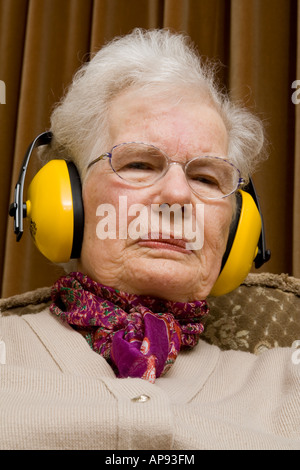 Ältere Dame tragen Ohr ^ Verteidiger und suchen ^ verärgert Stockfoto