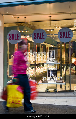 Eine Frau, die trägt January Sale Taschen vorbei an einem Schmuck Geschäft mit "Verkauf Aufkleber an den Fenstern in Dundee, Großbritannien Stockfoto