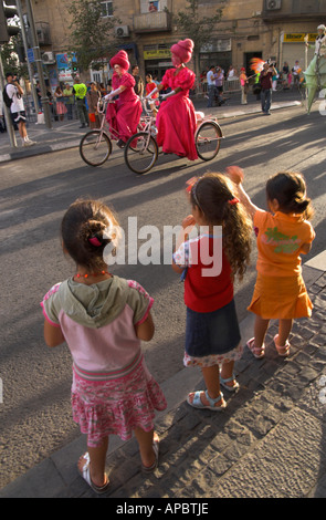 Israel Jerusalem City Center jährliche Jerusalem gehen 3 junge Mädchen winken 2 Radfahrer in rosa Kleider tragen Frauen verkleidet Stockfoto