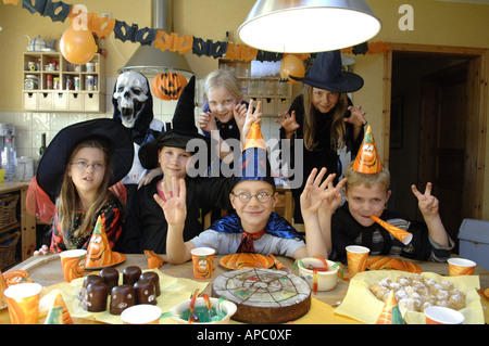 Kinder verkleideten sich zur Geburtstagsfeier, Halloween, als Geist, Hexen, Zauberer und Zombies und am Tisch sitzen Stockfoto