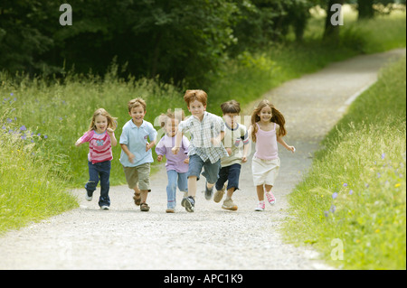 Gruppe von Kindern, die einen Weg in den Park laufen Stockfoto