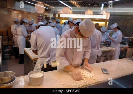 Ein Einblick in einer geschäftigen chinesischen Knödel Restaurantküche zeigt Köche bei der Arbeit macht Knödel hart Stockfoto