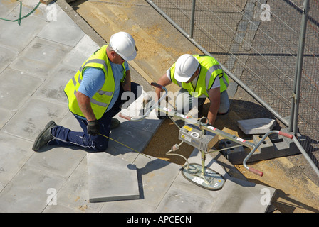 London-Pflaster, die Vermittlung In Arbeit zwei Arbeiter kniend neben Platte Hebewerkzeug Stockfoto