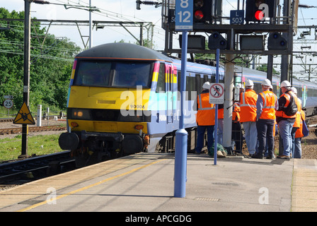 Das Wartungspersonal für Gruppengleise in gut sichtbaren Jacken wartet auf dem Bahnsteig, bis der Zug vorbeifährt, bevor es auf Gleis Essex England UK geht Stockfoto