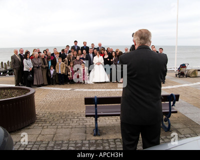 Hochzeitsfotograf, Gruppenfoto von Braut und Bräutigam und Gäste auf Aberystwyth Promenade, Wales, UK Stockfoto