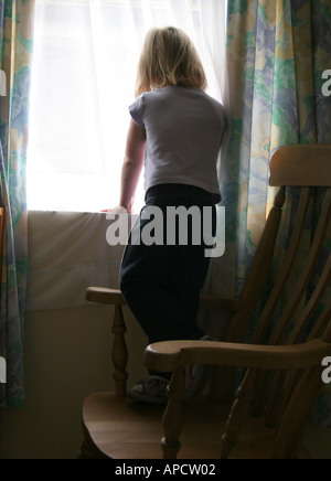 junges Mädchen spähte durch Fenster Stockfoto