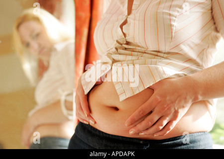 Frau Bauch im Spiegel betrachten Stockfoto