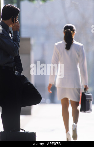 Geschäftsmann am Handy während die bewundernden vorbeifahrenden Frau sprechen Stockfoto