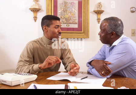 Midage Sohn hilft Vater mit Buchhaltung Stockfoto