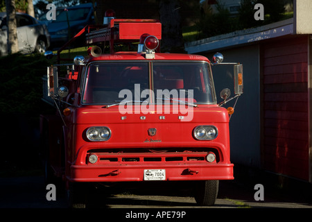 Ein rotes Feuerwehrauto sitzt im Schatten an einem Sommertag. Stockfoto