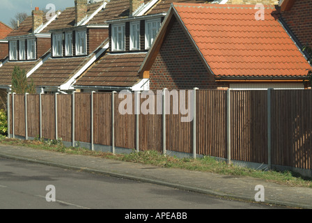 Wohnstraße mit neuen standard Holz Zaunverkleidungen Garten Grenze mit groben Rasen Rande Pflaster und Häuser Stockfoto