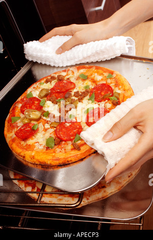 PIZZA ENTFERNEN AUS DEM OFEN Stockfoto