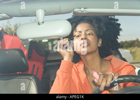 Afrikanerin, die Anwendung von Mascara in Auto Stockfoto