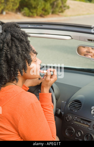 Afrikanerin Auftragen von Lippenstift in Auto Stockfoto