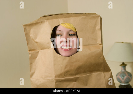 Blondes Teenies Mädchen trägt eine Tasche, mit einem Abschnitt Ausschneiden für ihr Gesicht, über den Kopf. Stockfoto