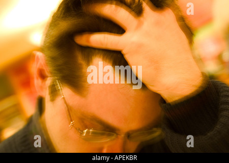 Nahaufnahme eines jungen Mannes, mit Brille, mit seiner Hand auf seinen Kopf. Stockfoto