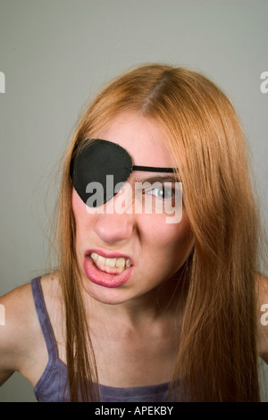 Junge Frau, mit langen roten Haaren, trägt eine Augenklappe und Grimassen.  -MODELL VERÖFFENTLICHT. Stockfoto