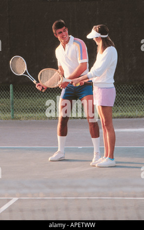 Junges Paar in Tennis Kleidung auf sonnigen Tennisplatz Schläger halten.  Mann Frau Schläger schwingen Anweisungen erteilen. Stockfoto