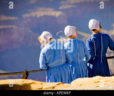 Amische Mädchen in traditionellen blauen Kleid und weiße Hüte mit Blick auf den Grand Canyon auf Sims mit Metall Geländer. (1) Stockfoto