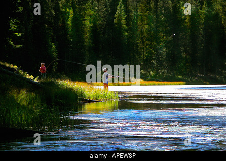 Junges Paar Darsteller Angeln am Ufer mit dunklen Wald im Hintergrund (in Colorado). Stockfoto