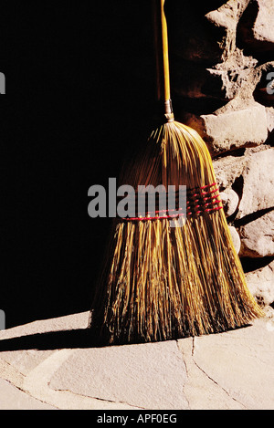 Altmodische Stroh Besen gelehnt Stein Säule, starke Seite Licht. Stockfoto