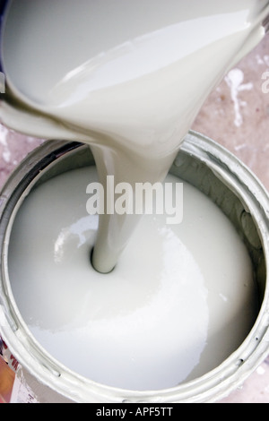 Farbe aus der Dose in einen Eimer gegossen wird. Stockfoto