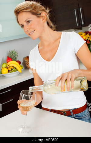 FRAU IN DER KÜCHE GIEßEN GLAS WEIN Stockfoto