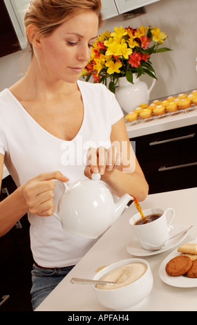 FRAU IN DER KÜCHE GIEßEN TEE Stockfoto