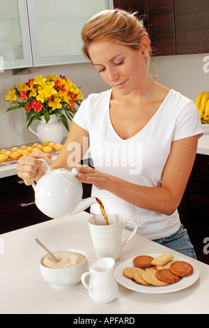 FRAU IN DER KÜCHE GIEßEN TEE Stockfoto