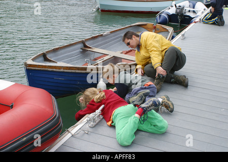 Familie Krabben fischen, liegend auf einem Steg in Dale Pembrokeshire Wales Großbritannien UK GB Stockfoto