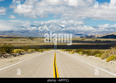 Gerader Weg zum entfernten schneebedeckten Berge in der Wüste in der Nähe von Palm Springs Kalifornien Stockfoto