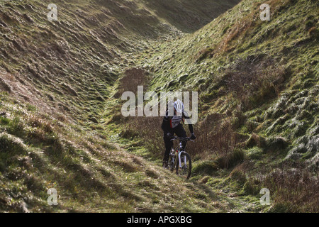 Lone Mountain Biker fährt eine Hintergrundbeleuchtung Trail in Wiltshire Stockfoto