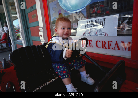 16 Monate altes Mädchen Spielzeug Auto auf Bürgersteig vor Geschäft in Fredericksburg, Texas Stockfoto