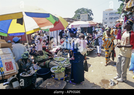 Auf dem Markt in Serekunda kauft die größte Stadt in Gambia eine Frau mit einem Baby auf dem Rücken etwas Gemüse Stockfoto