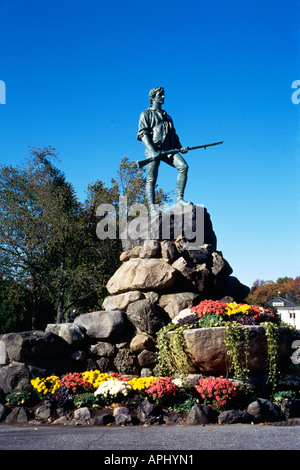 Die Statue von Captain Parker set vor einem strahlend blauen Himmel und auf der Oberseite einen großen Steingarten mit einer Masse von bunten Blumen und nachgestellte Efeu schmücken die Basis in Lexington s Village Green Stockfoto