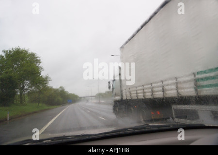 LKW überholen eines Autos im Regen auf der Autobahn M6 England Stockfoto