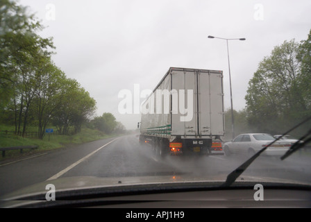 LKW überholen eines Autos im Regen auf der Autobahn M6 England Stockfoto