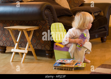 Stock Foto eine zweijährige auf ihr Töpfchen Töpfchentraining für ihr bedeutet, dass einen guten Haufen Bücher lesen neben ihr zu sitzen Stockfoto