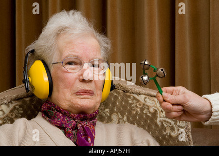 Ältere Dame tragen Ohr ^ Verteidiger und suchen ^ verärgert Stockfoto