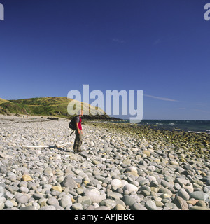 Männliche Wanderer zu Fuß an einem steinigen Strand Port Castle Bay Strand am Solway Firth in der Nähe von St Ninians Höhle in Schottland Stockfoto