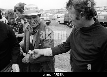 Geld wechselt die Hände eine Zahlung Zigeuner beim Derby Day Pferderennen Epsom Downs Surrey England 1974. Illegales Glücksspiel. 1970S GB HOMER SYKES Stockfoto