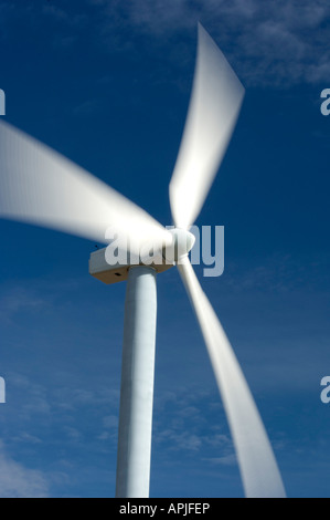 Die Rotorblätter einer Windkraftanlage spin vor blauem Himmel in einem Energie erzeugenden Unschärfe Stockfoto