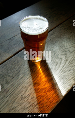 Ein Pint bitter stehend auf einem alten Holztisch in einem englischen pub Stockfoto